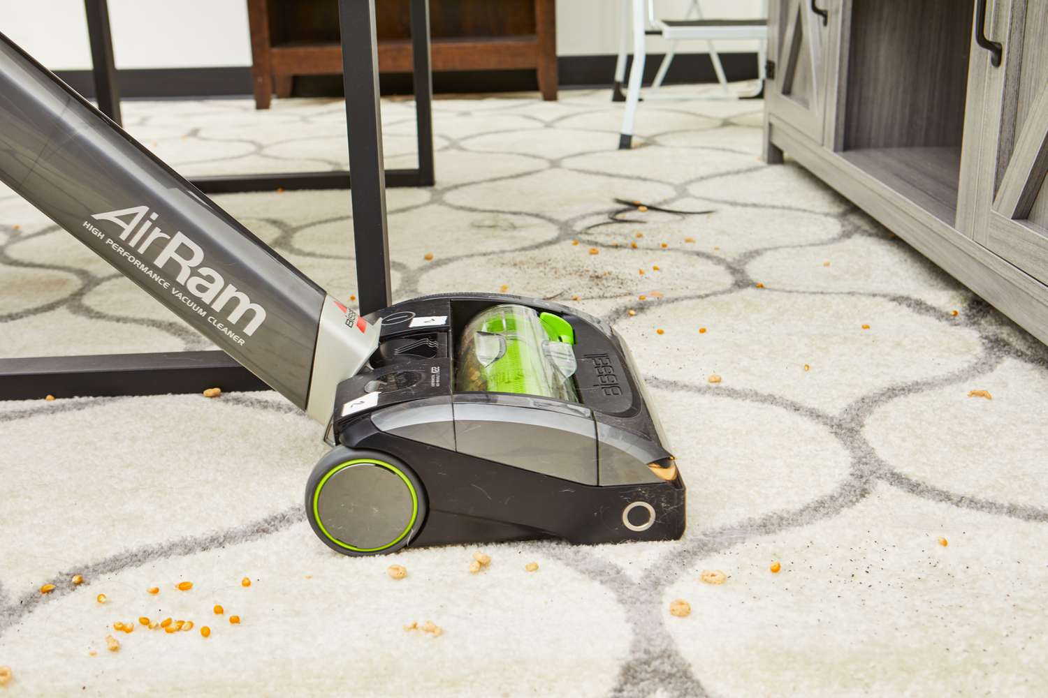 A person vacuums food off a rug using the Bissell 1984 Air Ram Cordless Vacuum.