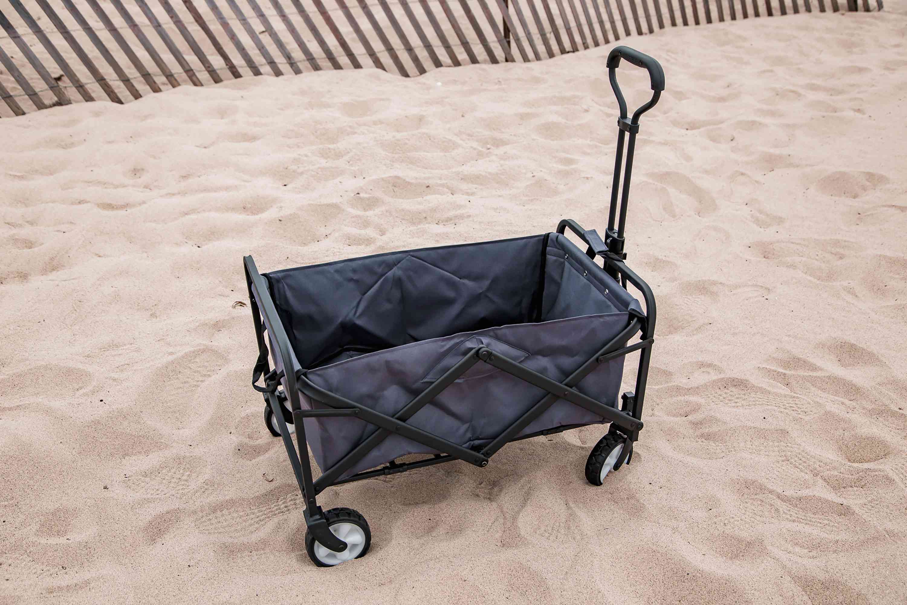 Whitsunday Collapsible Folding Cart displayed on a sandy beach with nearby sand fence