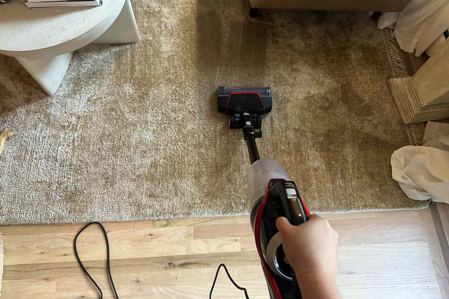 A person uses the Bissell CleanView Pet Slim Corded Stick Vacuum to clean a rug