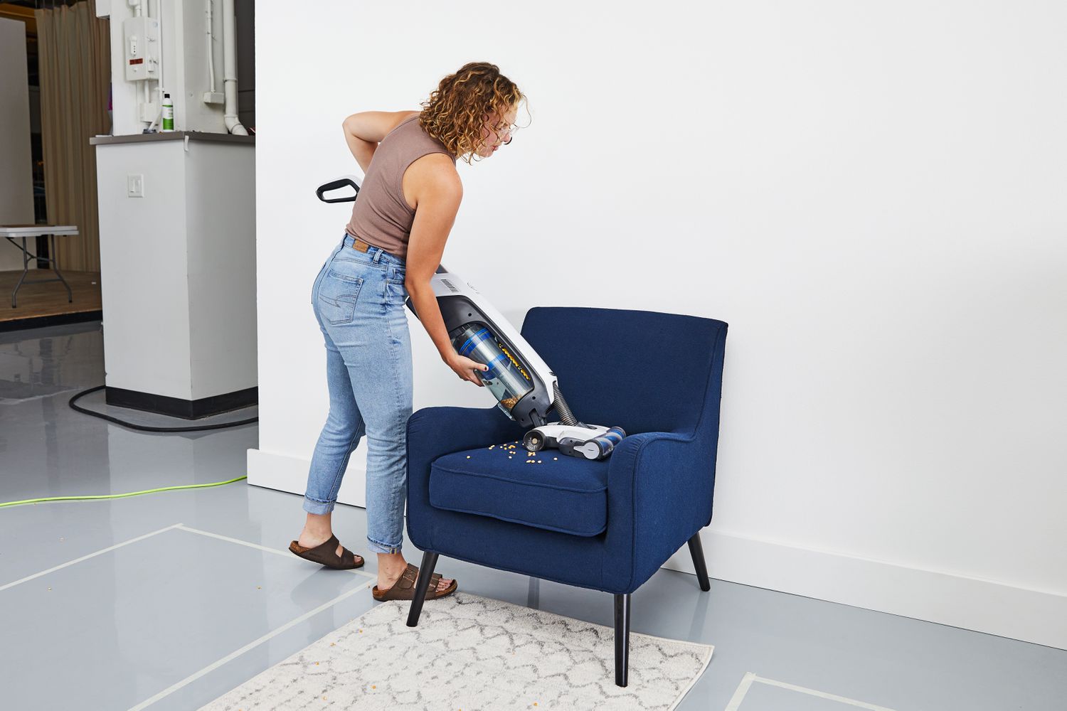 Woman vacuuming food from chair with Hoover Onepwr Evolve Pet Cordless Vacuum