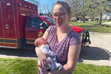 Kathryn and Jordan Norsigian, center, delivered their newest child in the passenger seat of their car Friday, April 5, 2024 with the help of the Farmington Hills Fire Department. Here reunited on April 8 with baby Jordan a boy.