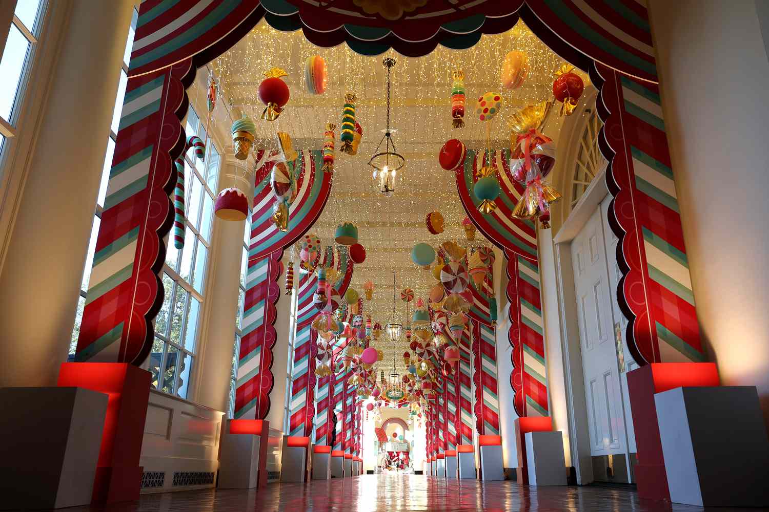 Candy-themed ornaments hang from the ceiling of the hallway between the East Wing and the Residence during a media preview of the holiday decorations at the White House November 27, 2023