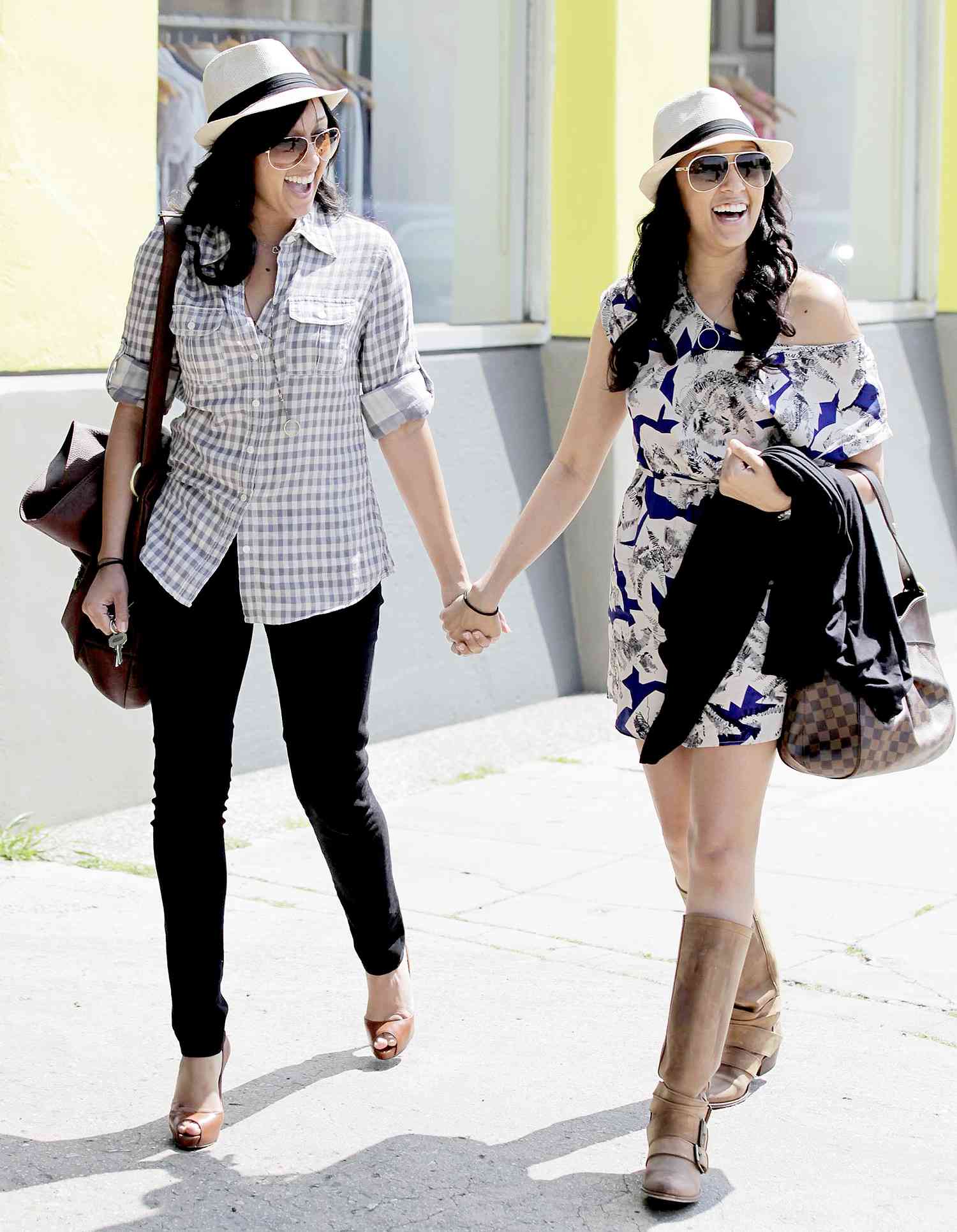 TIA AND TAMERA MOWRY SMILING AND HOLDING HANDS