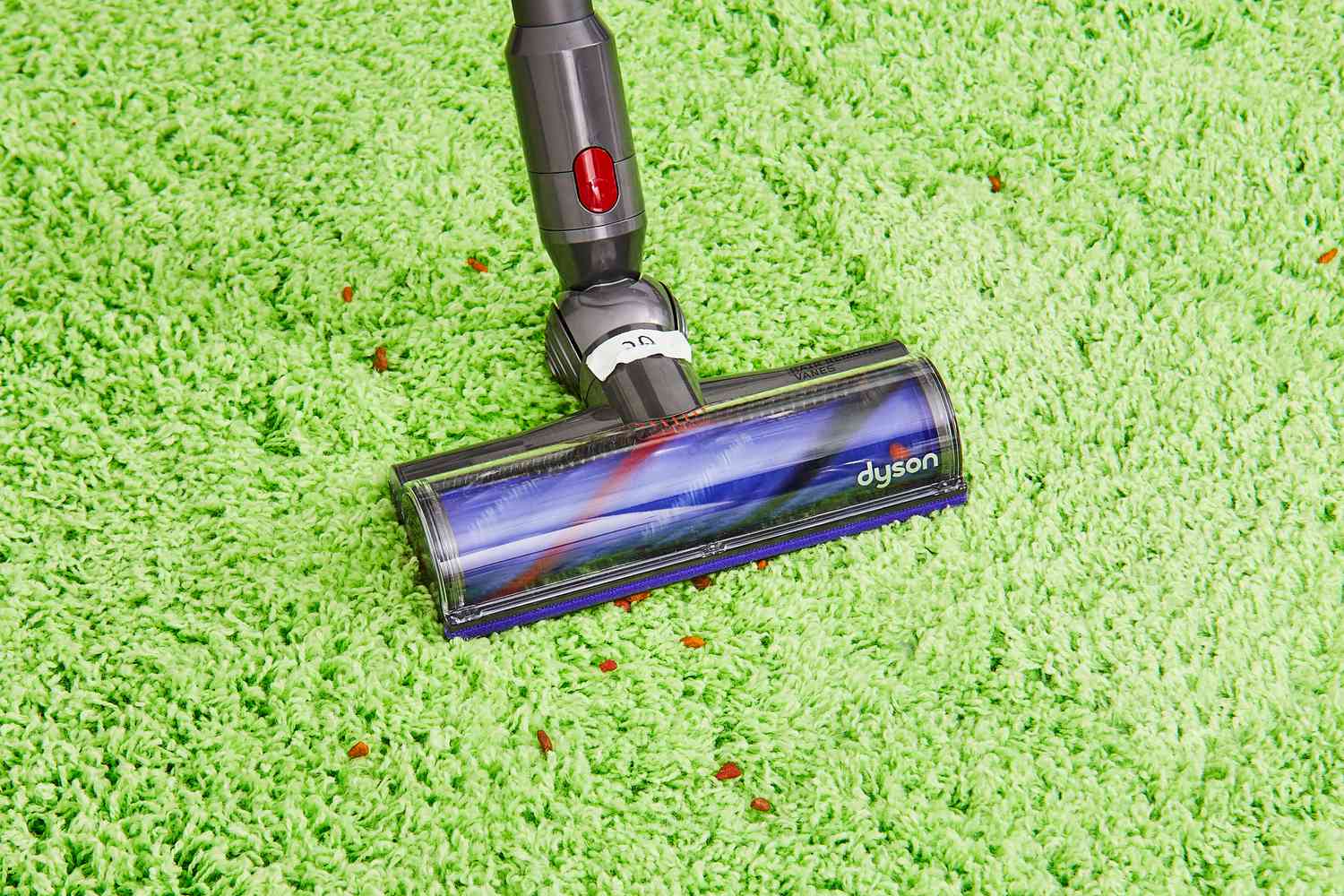 Dyson Cyclone V10 Animal Cordless Stick Vacuum cleaning pet food from green rug