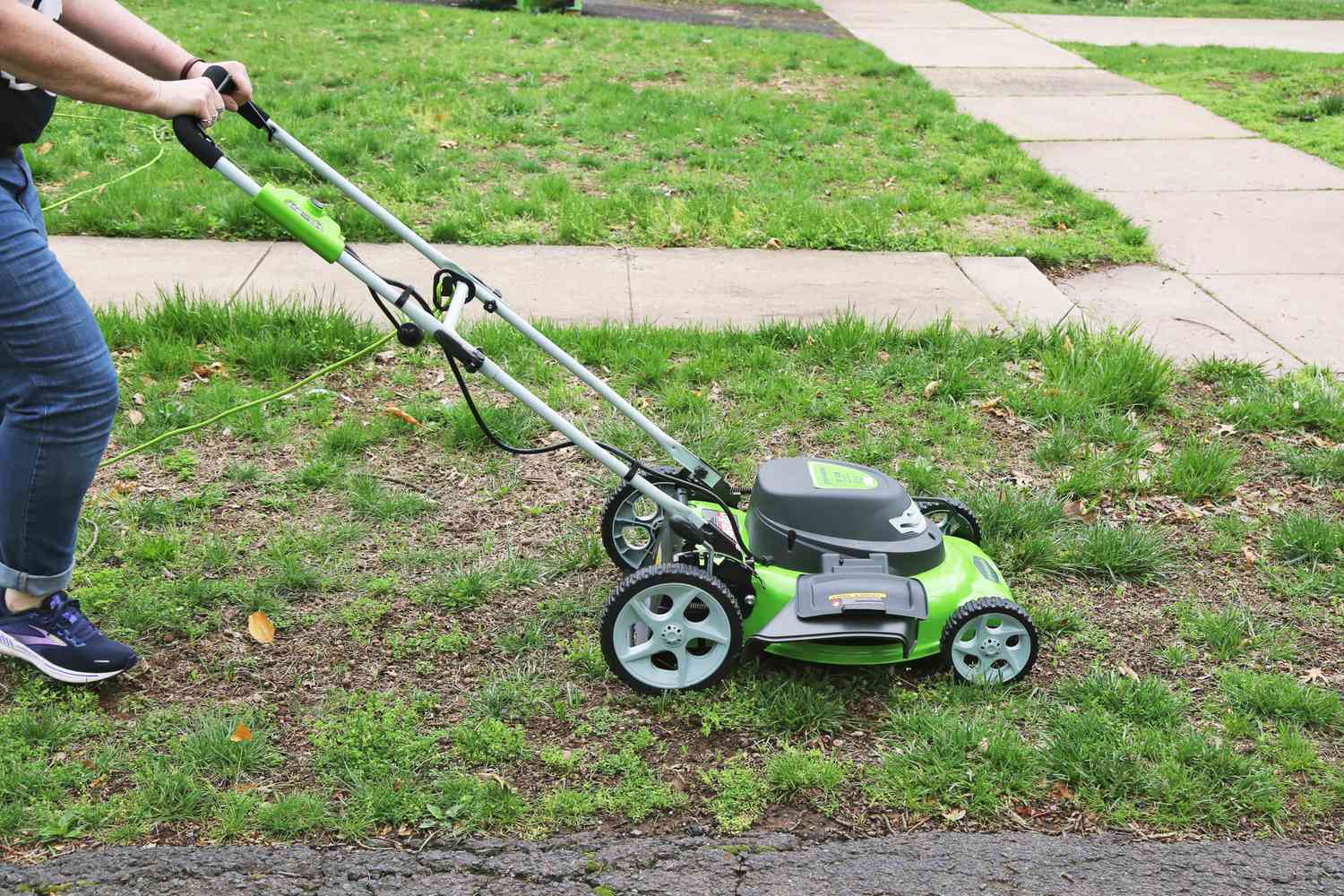 Person pushing Greenworks 25022 12-Amp 20-Inch 3-in-1 Corded Lawn Mower across a lawn