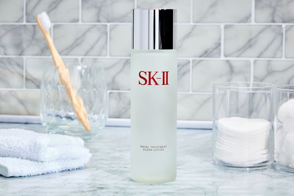 SK-II Facial Treatment Clear Lotion Toner displayed on a bathroom counter next to a glass container of cotton pads