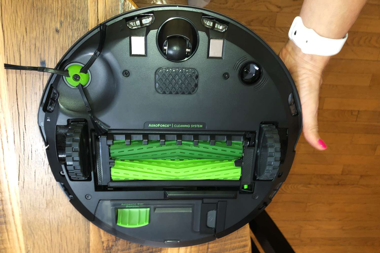 Person's hand holds out iRobot Roomba J7 Robot Vacuum to display bottom parts