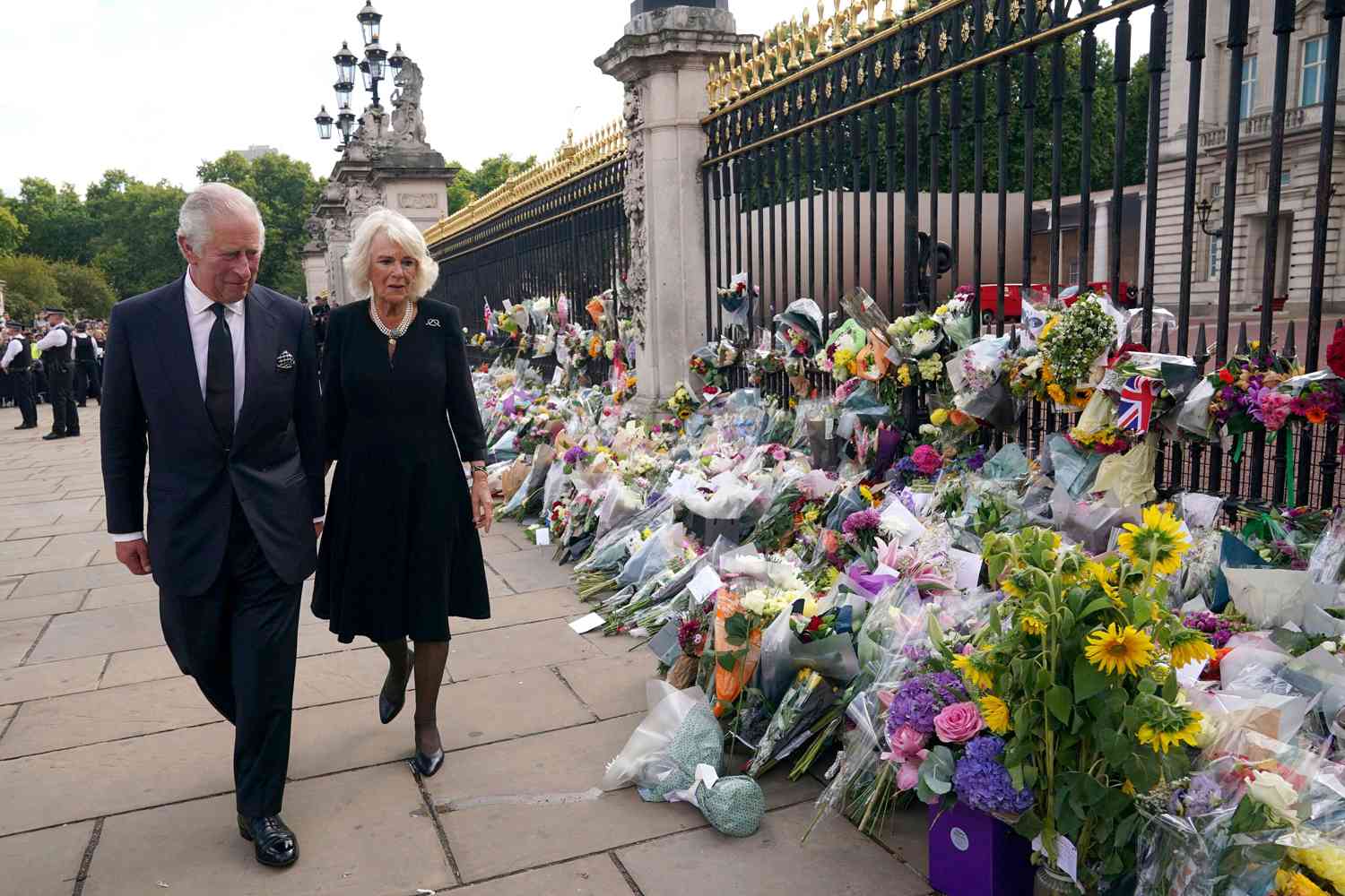 King Charles III, left, and Camilla, the Queen Consort, walk past floral tributes left outside Buckingham Palace following Thursday's death of Queen Elizabeth II, in London,