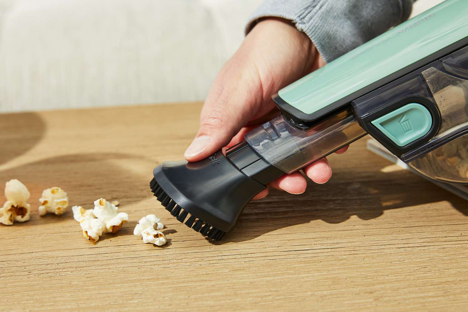 Closeup of hand using the Shark UltraCyclone Pro Cordless Handheld Vacuum to clean popcorn from wooden table