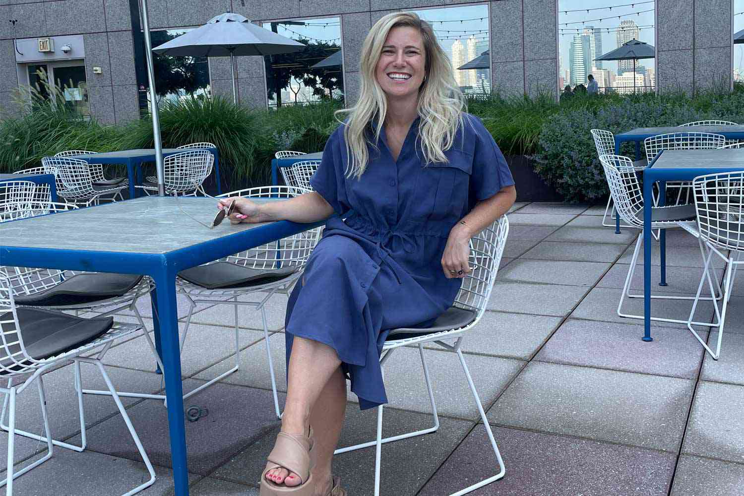 A person wearing a linen dress while sitting at a table on a restaurant patio. 