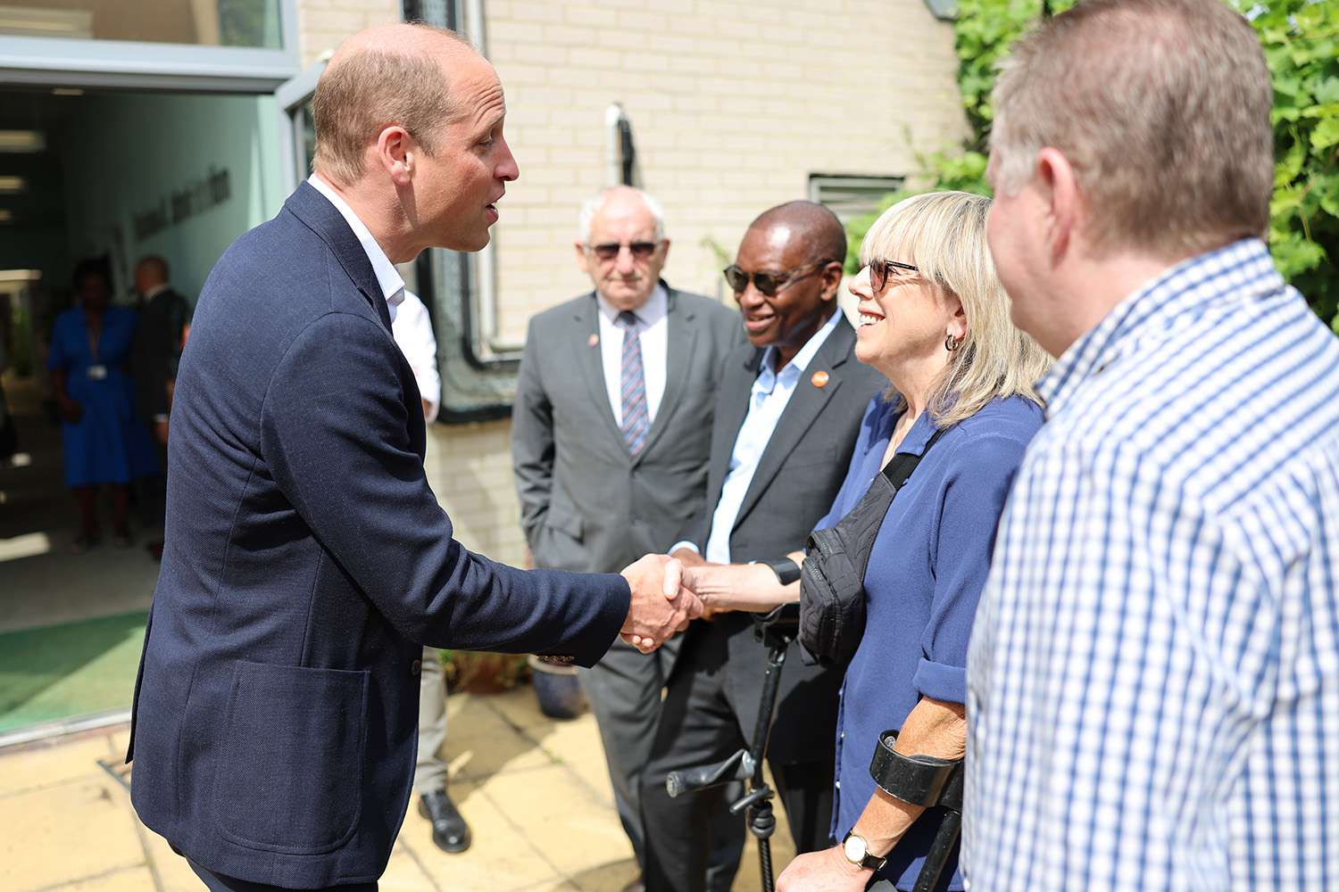 Prince William, Prince of Wales shakes hand with a member during his visit to Mosaic Clubhouse