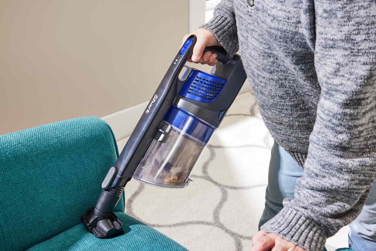 A person vacuuming a chair with the Shark Pet Cordless Stick Vacuum with XL Dust Cup