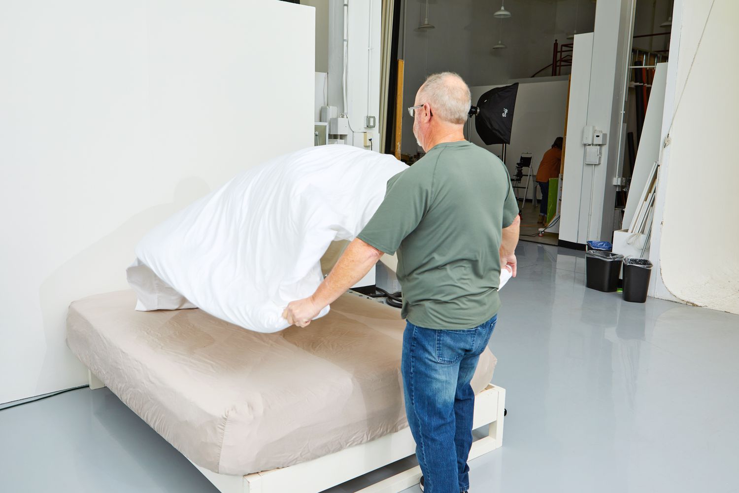 Person tossing a Brooklinen Luxury Sateen Duvet Cover over a bed