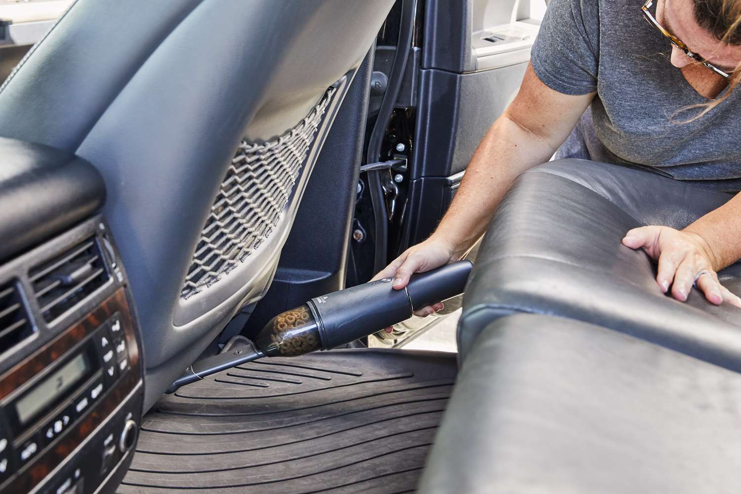 person cleans under car seat with BISSELL AeroSlim Lithium Ion Cordless Handheld Vacuum