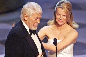 James Coburn holds up his Oscar after winning for Best Performance by a Supporting Actor in a Leading Role for his part in the movie "Affliction" during the 71st Academy Awards 21 March 1999 at the Dorothy Chandler Pavilion. Presenting the Oscar is Kim Basinger. (ELECTRONIC IMAGE) AFP PHOTO/Timothy A. CLARY (Photo by Timothy A. CLARY / AFP) (Photo by TIMOTHY A. CLARY/AFP via Getty Images)