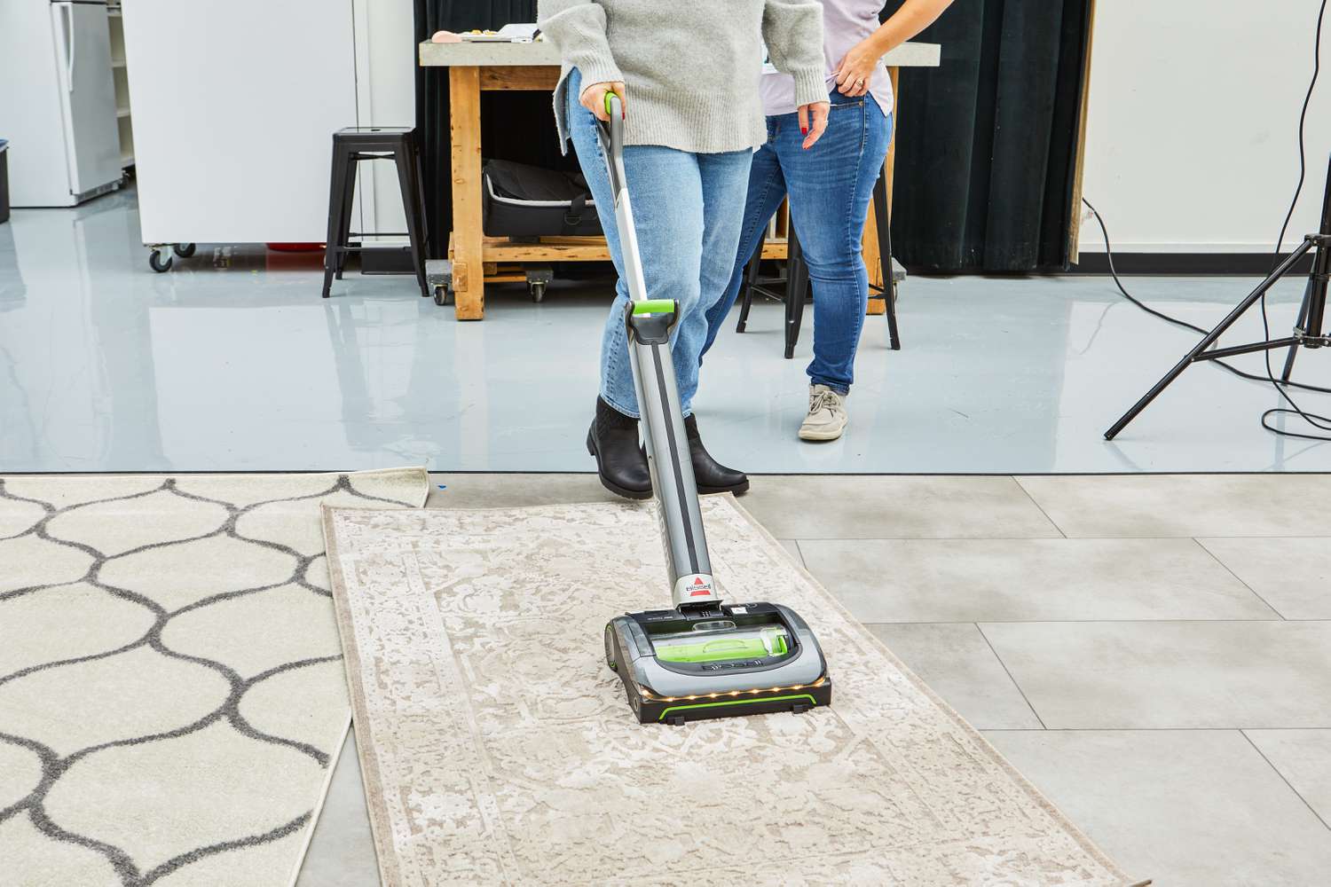 A person vacuums a rug using the Bissell 1984 Air Ram Cordless Vacuum.