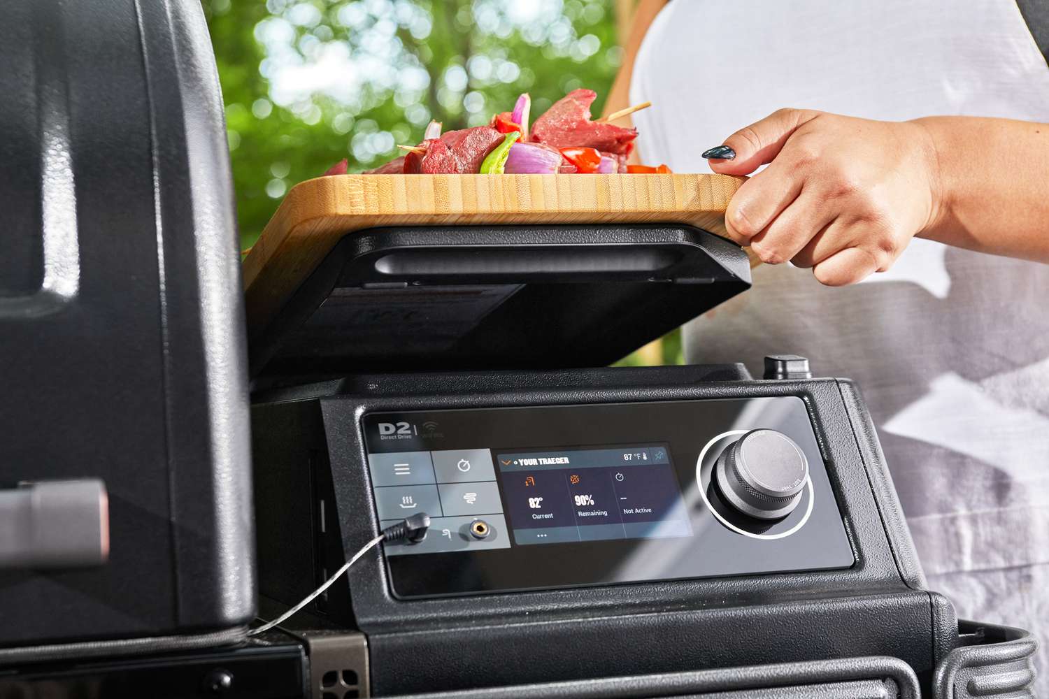 Hand lifting the lid of a side compartment on the Traeger TBB86RLG Timberline Pellet Grill