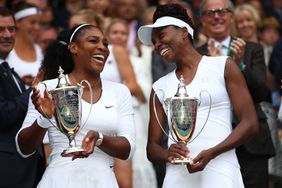 Venus Williams of The United States and Serena Williams of The United States hold their trophies following victory in the Ladies Doubles Final against Timea Babos of Hungary and Yaroslava Shvedova