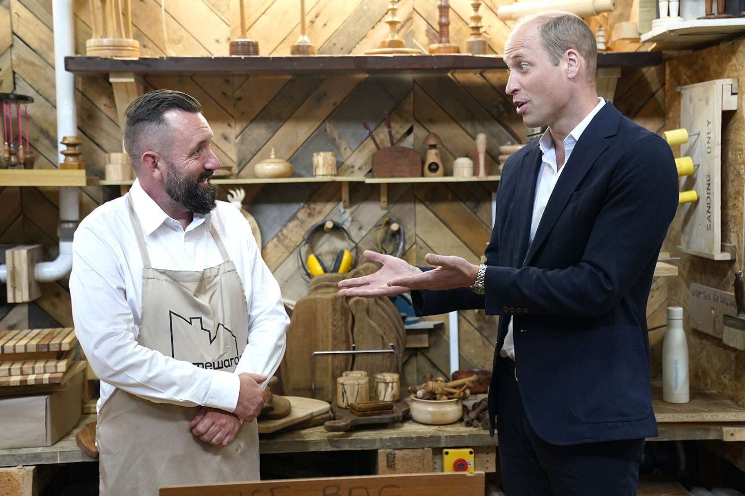 Prince William, Prince of Wales talks to people during a visit to Faithworks Carpentry Workshop