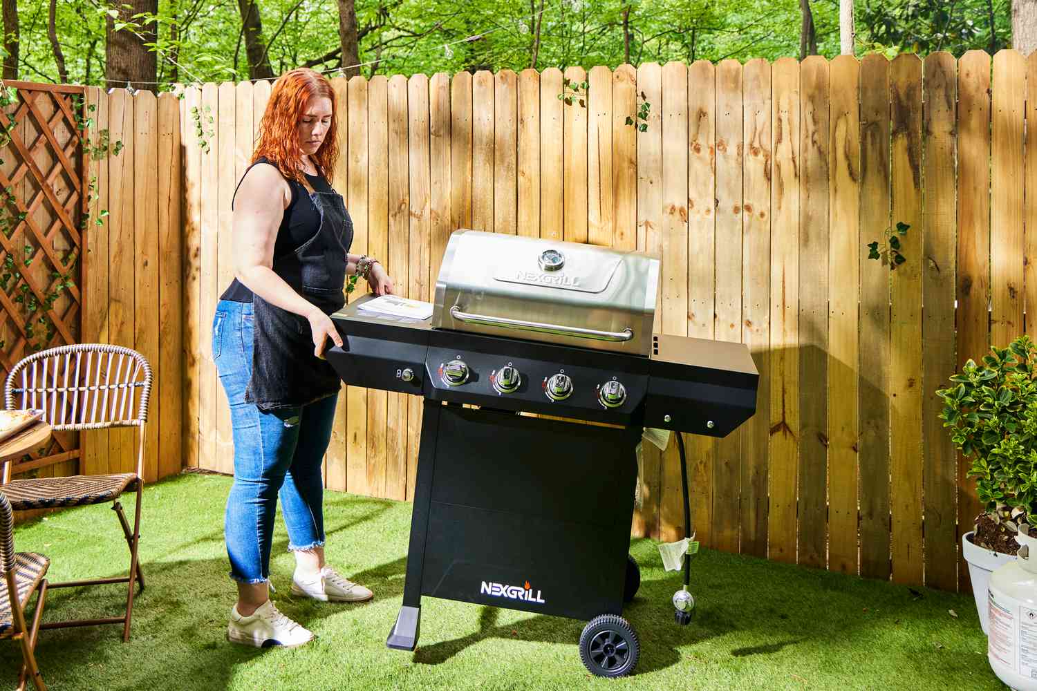 A person lifts the side of the Nexgrill 4 Burner Propane Gas Grill