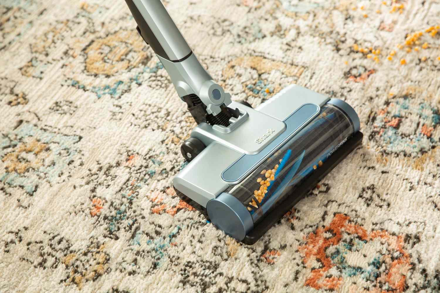 Close up of Shark Vertex Lightweight Cordless Stick Vacuum with DuoClean PowerFins vacuuming corn kernels from carpet