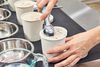 Person scooping ice cream from first in a line of ice cream pints in front of metal bowls