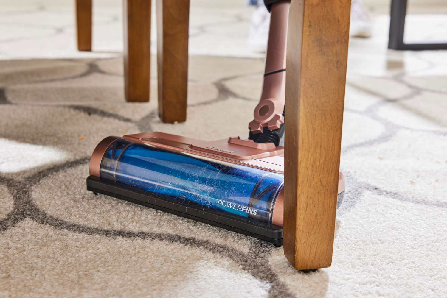 A close-up of the Shark Wandvac cleaning a rug under a table