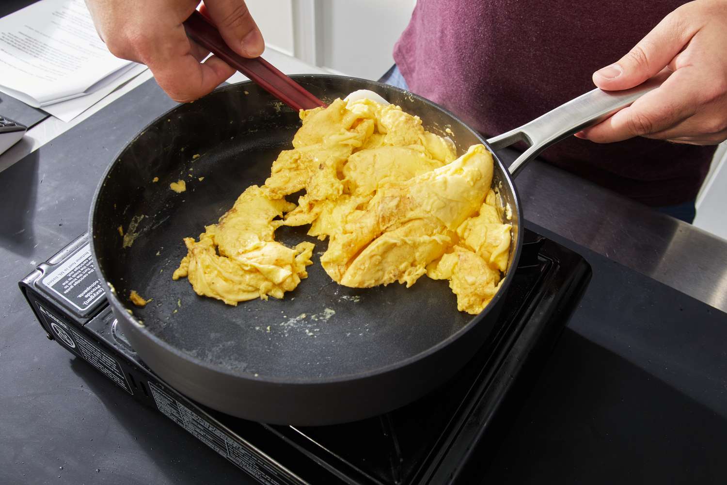 Hand using spatula to cook scrambled eggs in Calphalon Classic Hard-Anodized Nonstick 10-Piece Cookware Set saute pan