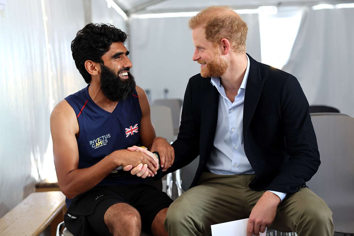 Prince Harry, Duke of Sussex meets competitor Wali Noori as he attends the track and field at the athletics track during day two of the Invictus Games