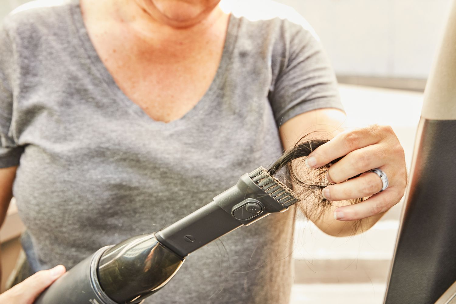 hand removing clump of hair from BISSELL AeroSlim Lithium Ion Cordless Handheld Vacuum