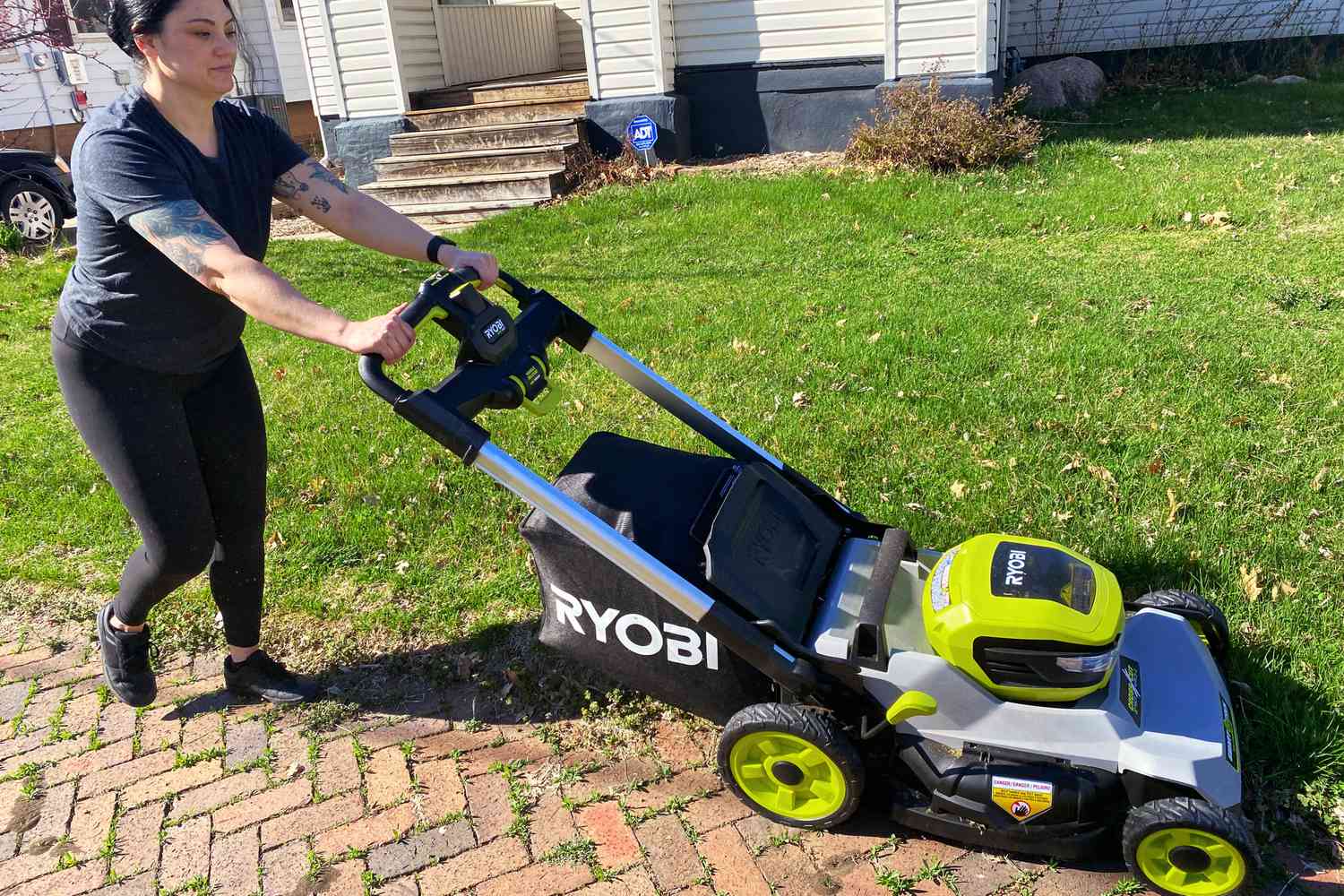 Woman mowing a lawn using the Ryobi 40V HP Brushless 21-Inch Dual-Blade Self-Propelled Mower
