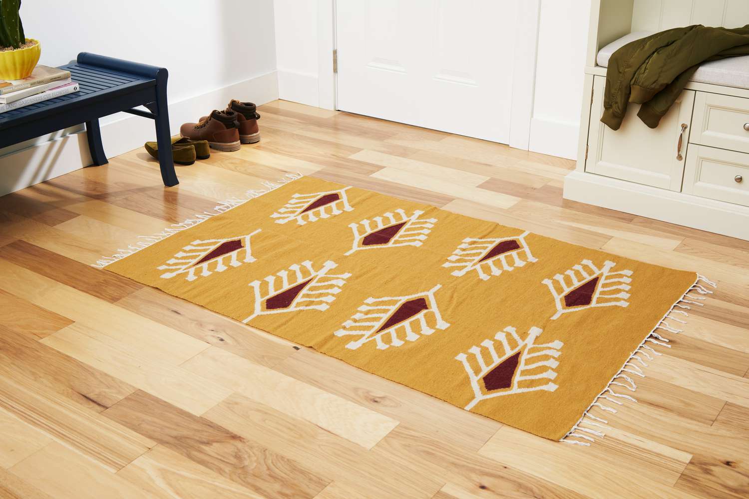 The 54 Kibo Cypress Mustard Floral Area Rug on a wooden floor