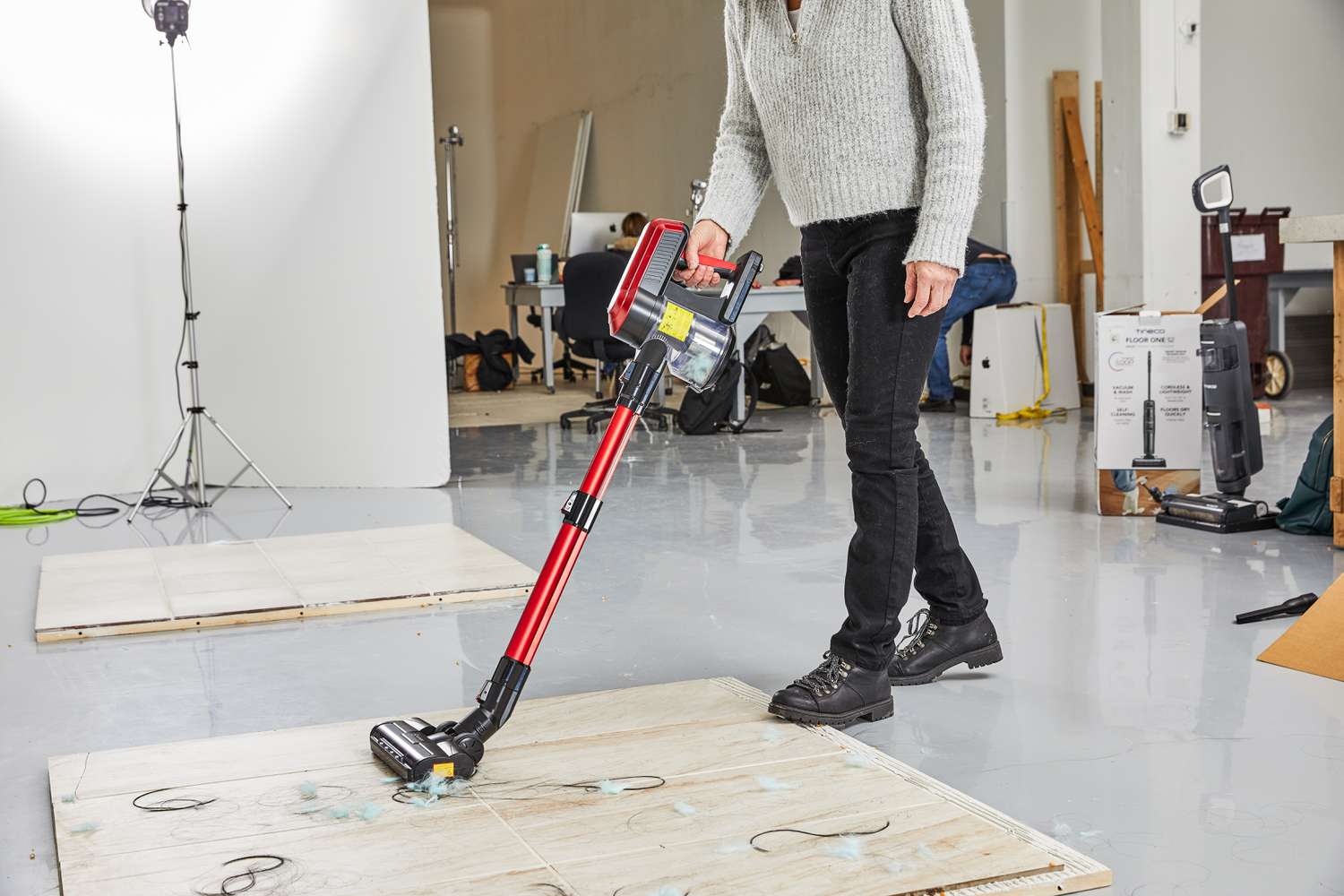 Person using the Moosoo K23 Pro Cordless Stick Vacuum to clean hair and fuzz from tile floor 