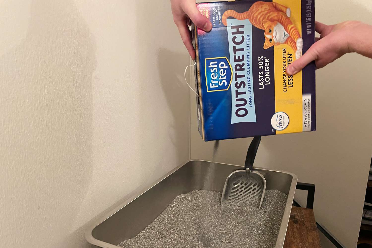 hands pouring Fresh Step Outstretch Long Lasting Concentrated Clumping Cat Litter with Febreze Freshness into litter box