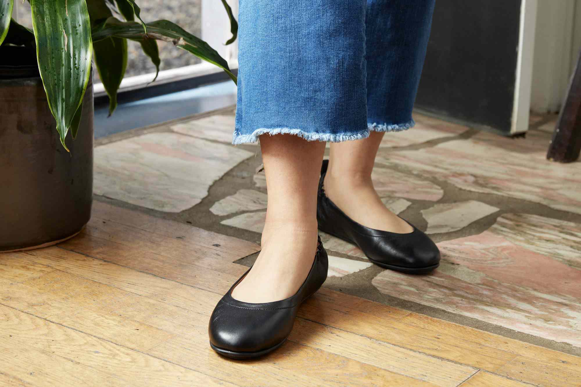 A pair of legs with black FitFlop Allegro Ballet Flats on feet