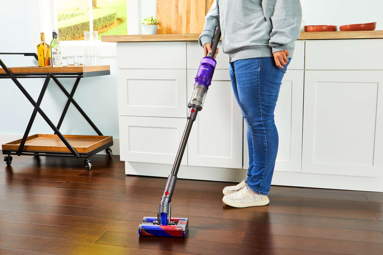 Person using a Dyson Omni-Glide Cordless Vacuum to clean hardwood floor