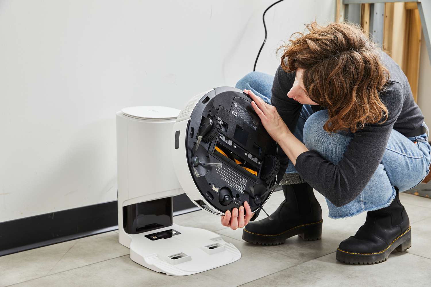 A person inspects the bottom of the Ecovacs Deebot T9+ Robot Vacuum and Mop Combo