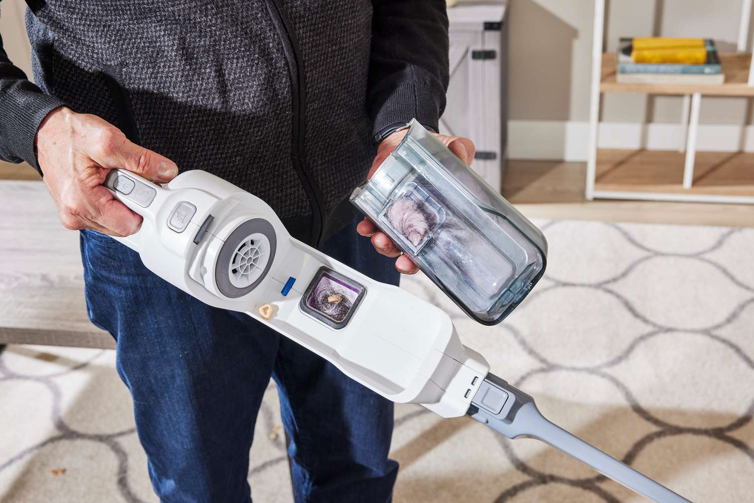 The Black + Decker Powerseries+ 16V MAX Cordless Stick Vacuum with its dirt pouch removed into a person's hand