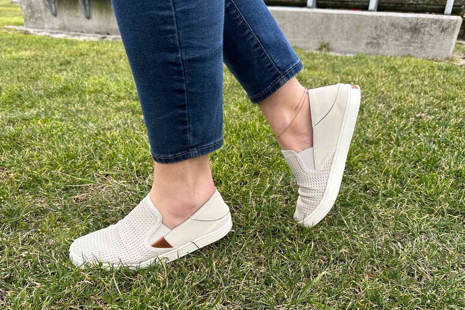 Person wearing the OluKai Pehuea Slip On Sneakers on grass