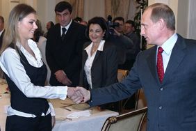 Russian President Vladimir Putin (R) shakes hands with famous Russian gymnasts Alina Kabayeva (C) and Svetlana Khorkina (L) during the meeting with sportsmen, candidates to Russian Olympic team for Olympics 2004, in the presidential residence in Novo-Ogaryovo outside Moscow, 10 March 2004. Vladimir Putin said Russian business is ready to support Russian sportsmen. AFP PHOTO / POOL (Photo credit should read SERGEI CHIRIKOV/AFP via Getty Images)