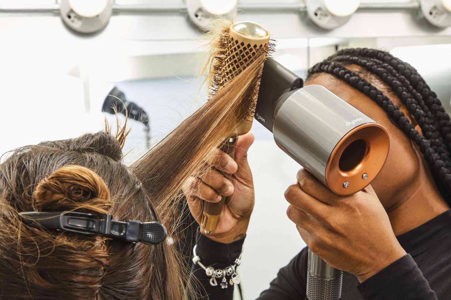 Woman using a Dyson Supersonic Hair Dryer on another persons hair with a brush