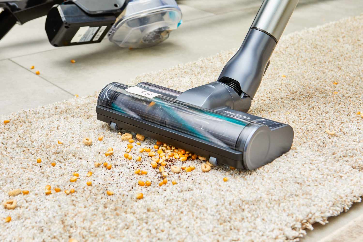 Samsung Jet 75 Cordless Stick Vacuum cleaning food from a beige carpet 