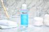 Murad Clarifying Toner on a marble counter next to cotton pads in container and a towel 