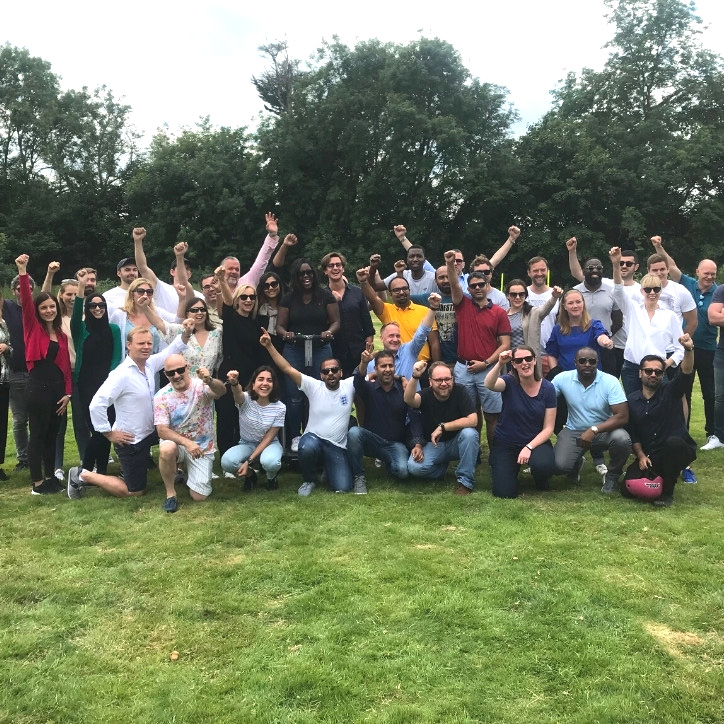 Large crowd of smiling PubMatic employees with their hands in the air