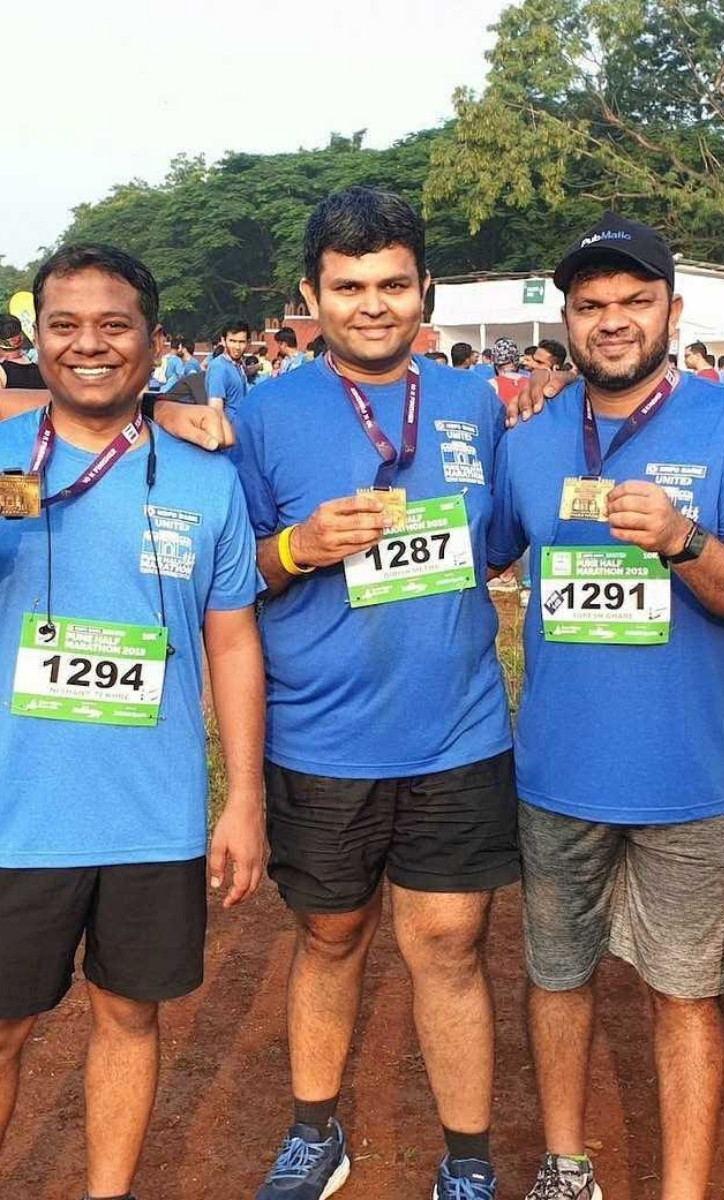 Three smiling men standing outside a race.