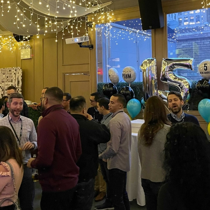 A crowd of people chatting and eating at a work party.