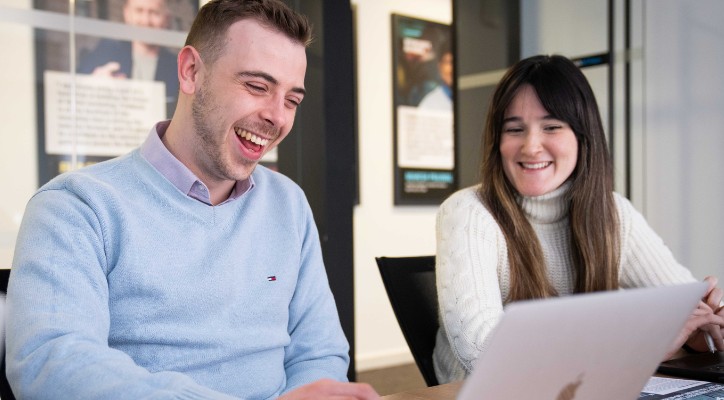 A smiling man and woman seated within an office