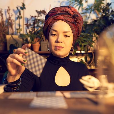 Female enchantress spreading tarot cards at table