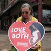 A woman holds an anti-abortion placard as she kneels in