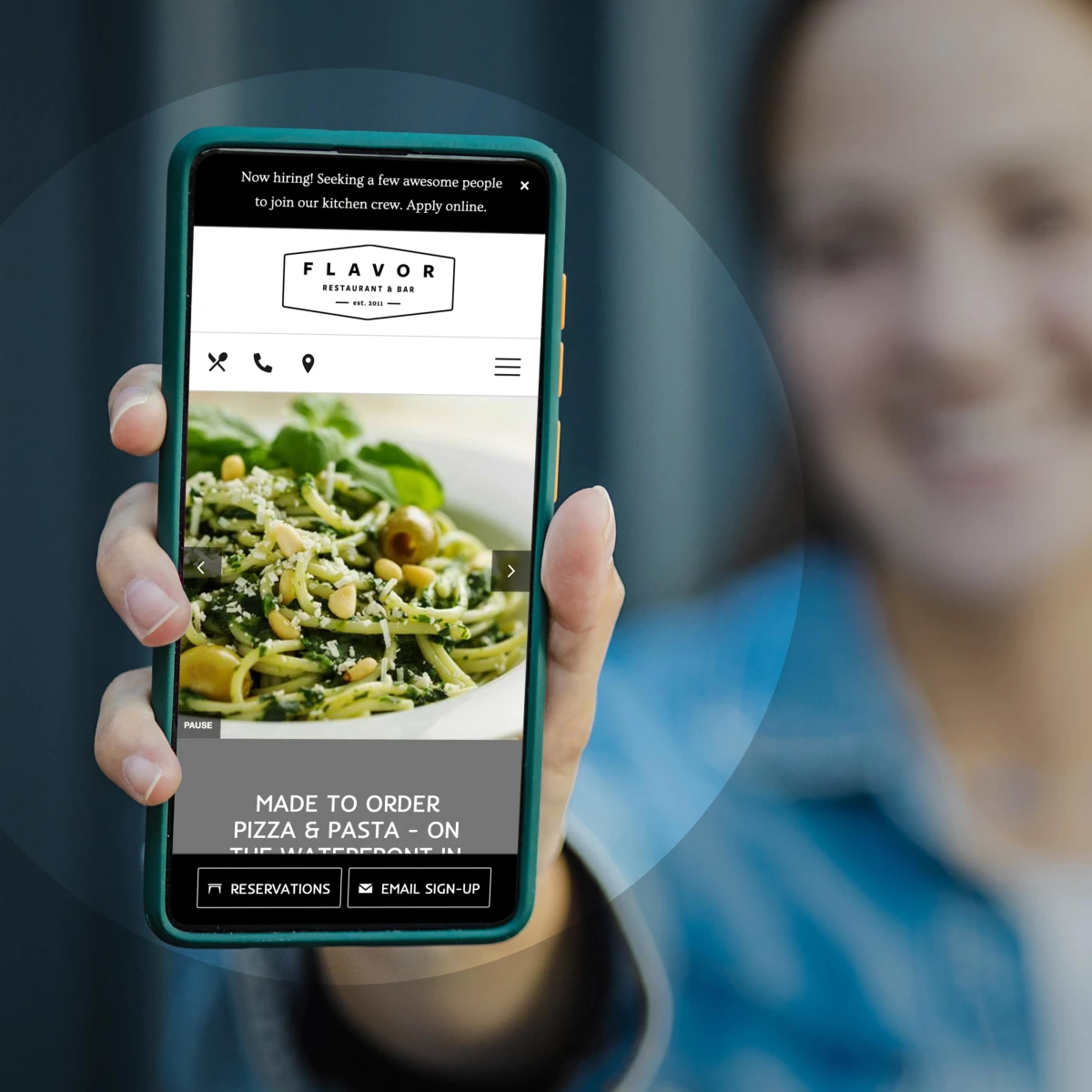 young woman holding a smartphone showing a restaurant website